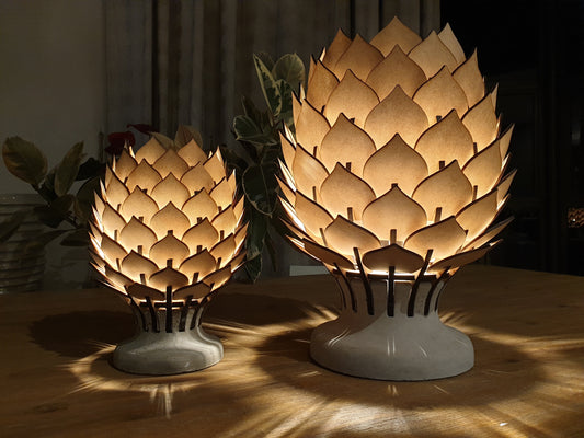 Two artichoke-shaped lamps on a wooden surface with a blurred background