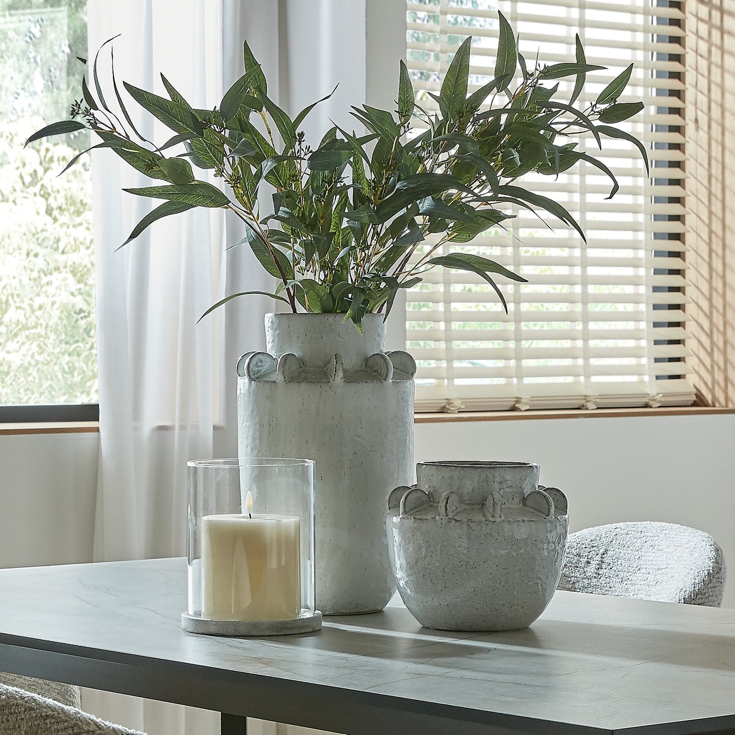 Decorative vases with a candle on a table near a window
