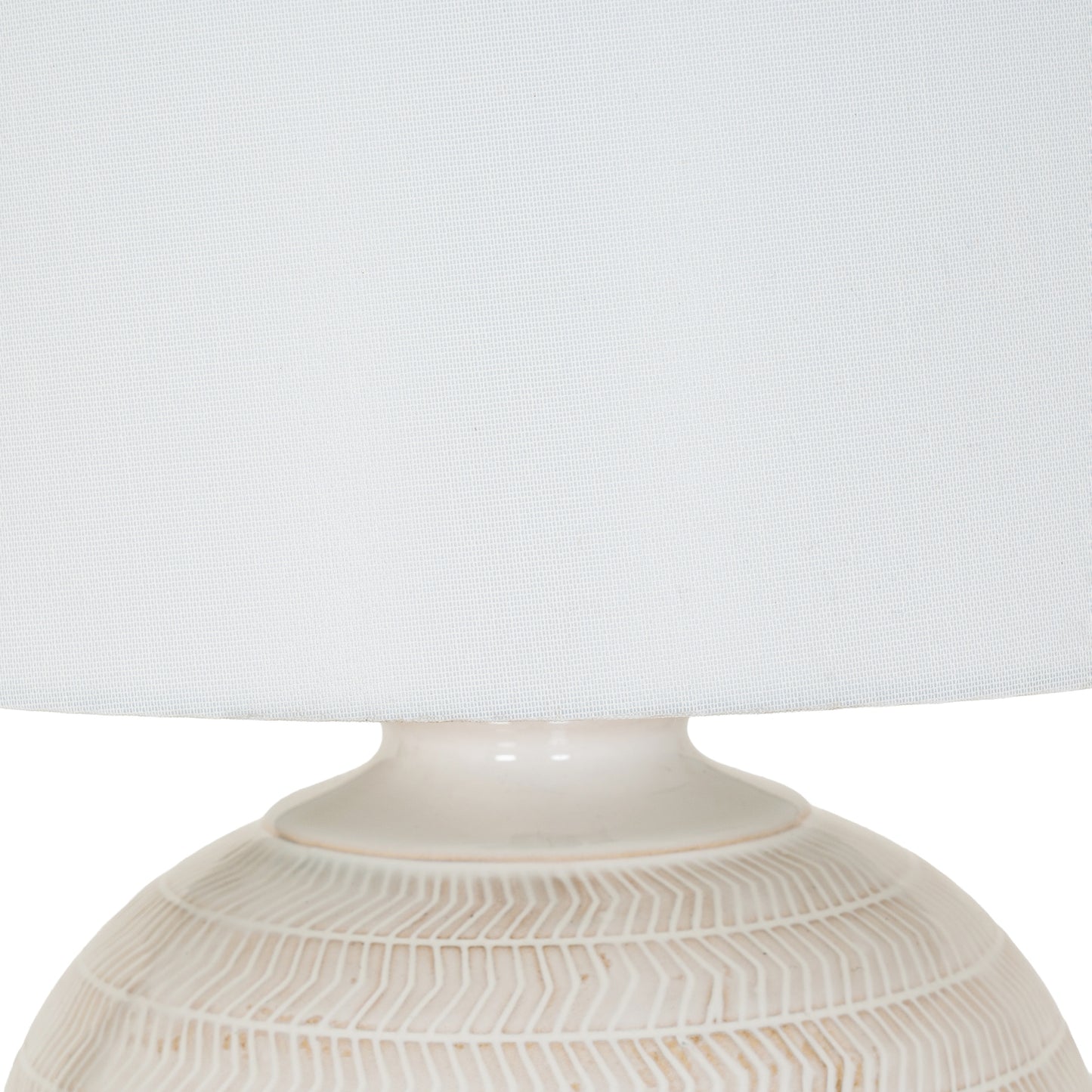 Close-up of a textured ceramic lamp base with a white lampshade on a light gray background