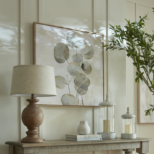 Decorative table setting with a lamp, books, and candle holders on a wooden surface.