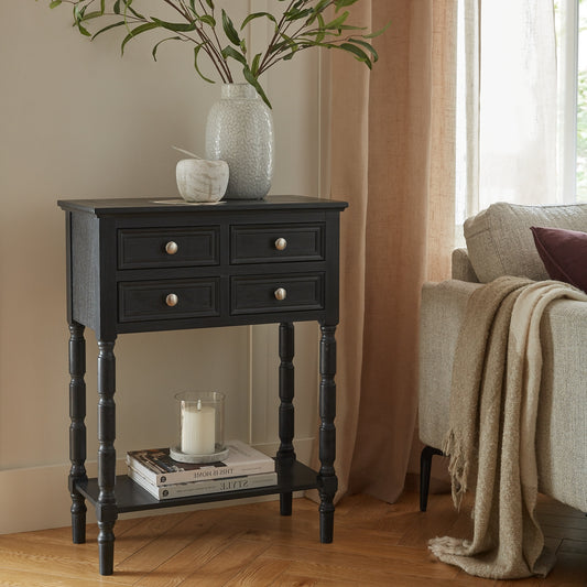 Black side table with decorative items in a living room setting
