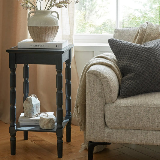 Cozy living room with a beige sofa, side table, and decorative items.