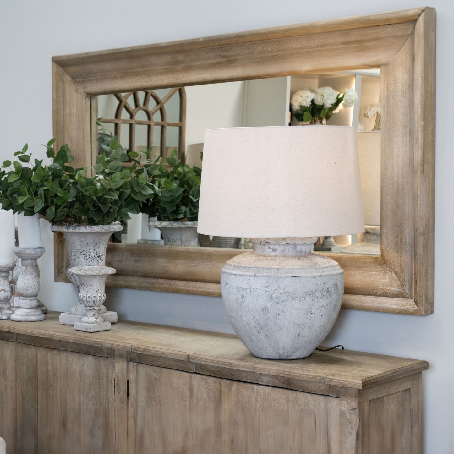 Decorative lamp on a wooden console table with a large mirror in the background.