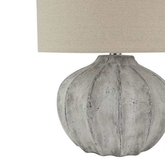 Table lamp with textured gray base and beige lampshade on a white background
