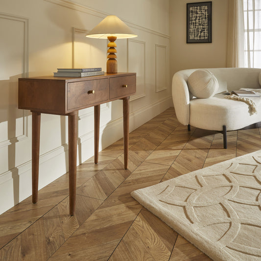 Wooden console table with a lamp and books in a living room setting.