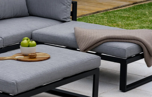 Gray outdoor sofa with cushions and a blanket on a patio