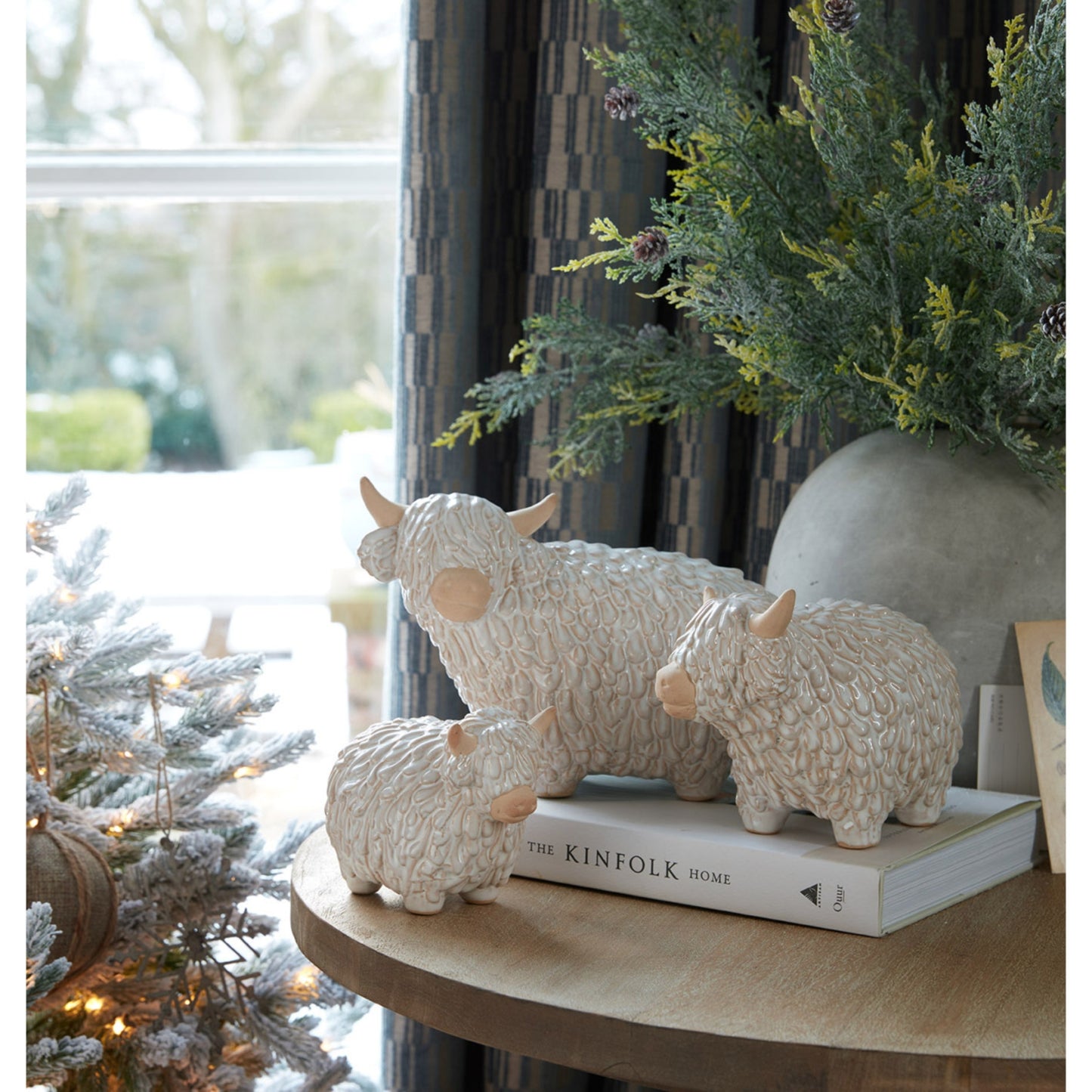 Decorative sheep figurines on a book with a Christmas tree in the background