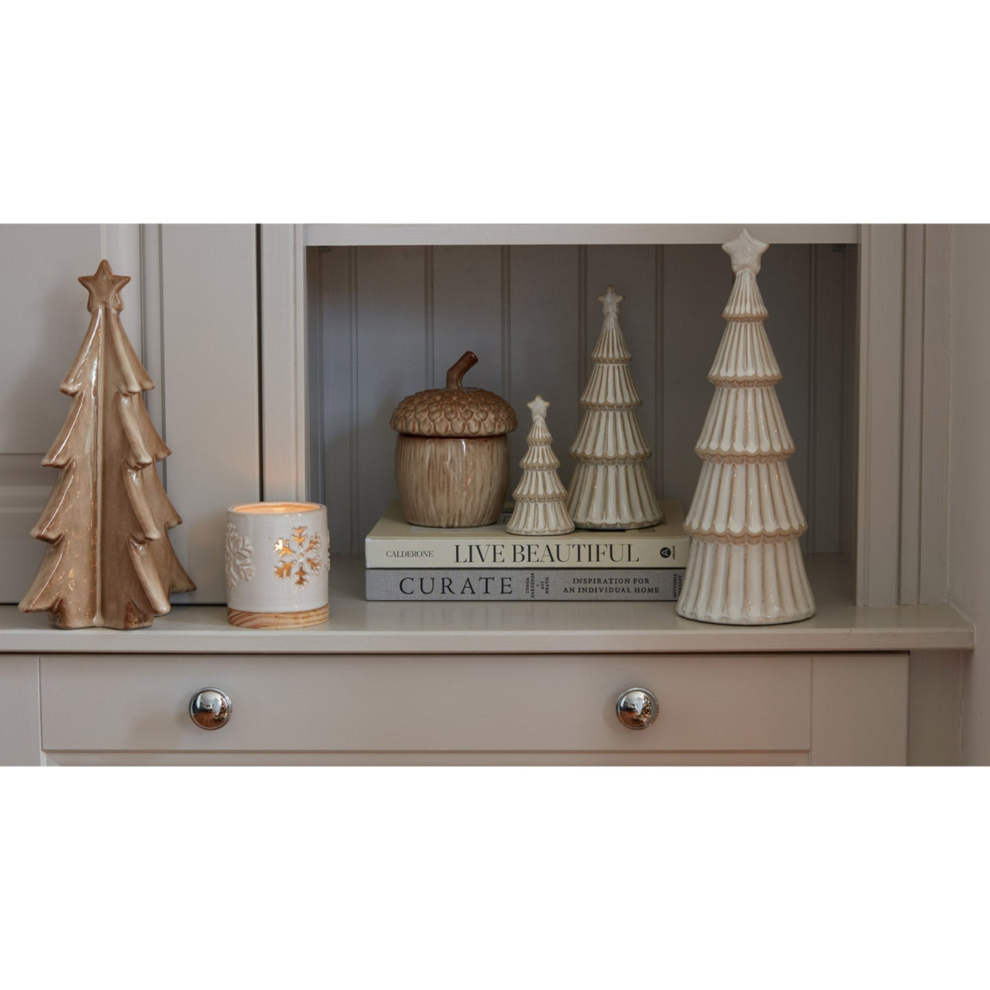 Decorative items including trees and a candle on a shelf with a neutral background