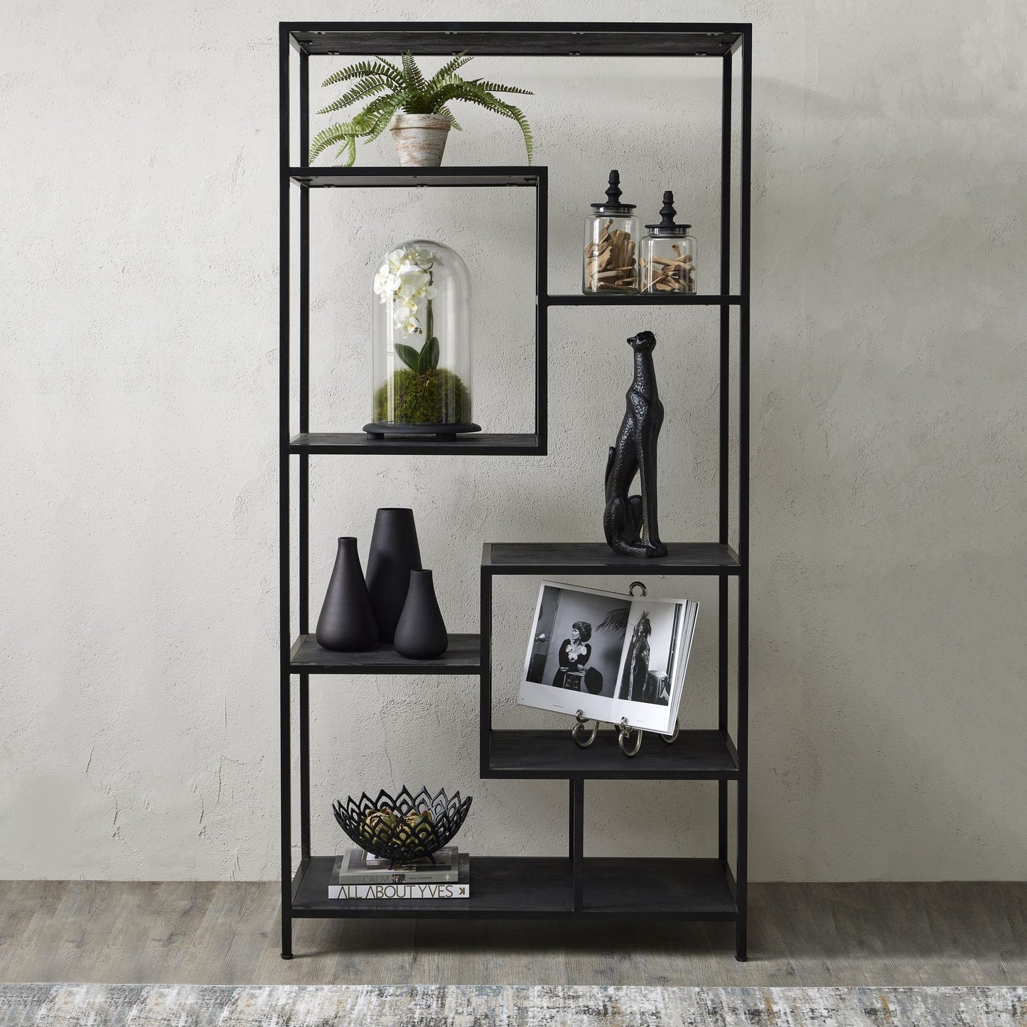 Black metal shelf with decorative items against a plain wall