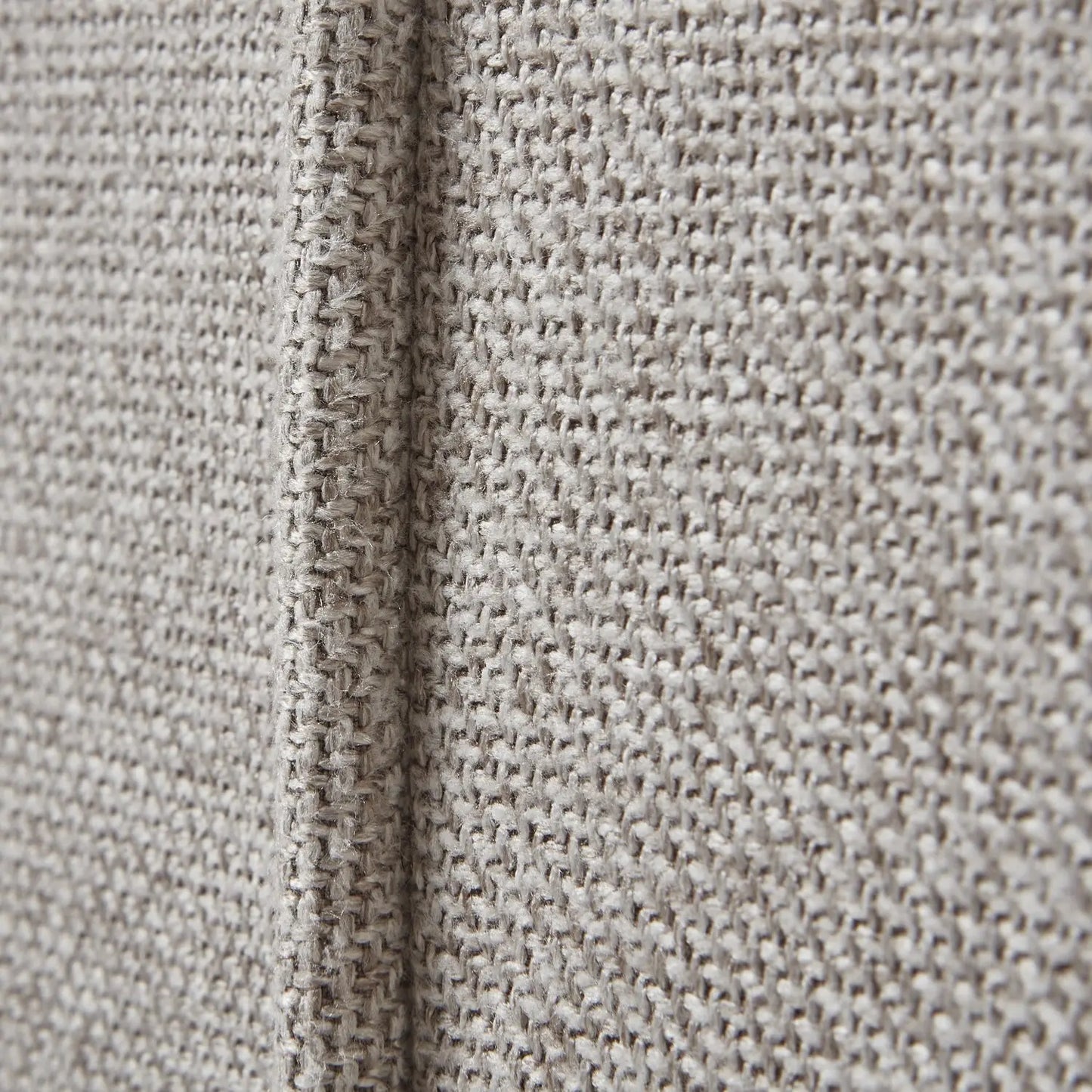 Close-up of textured beige fabric with a visible seam.