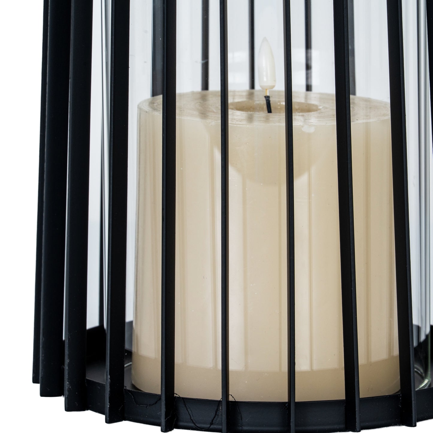 White candle in a black metal lantern with sheer white curtains in the background
