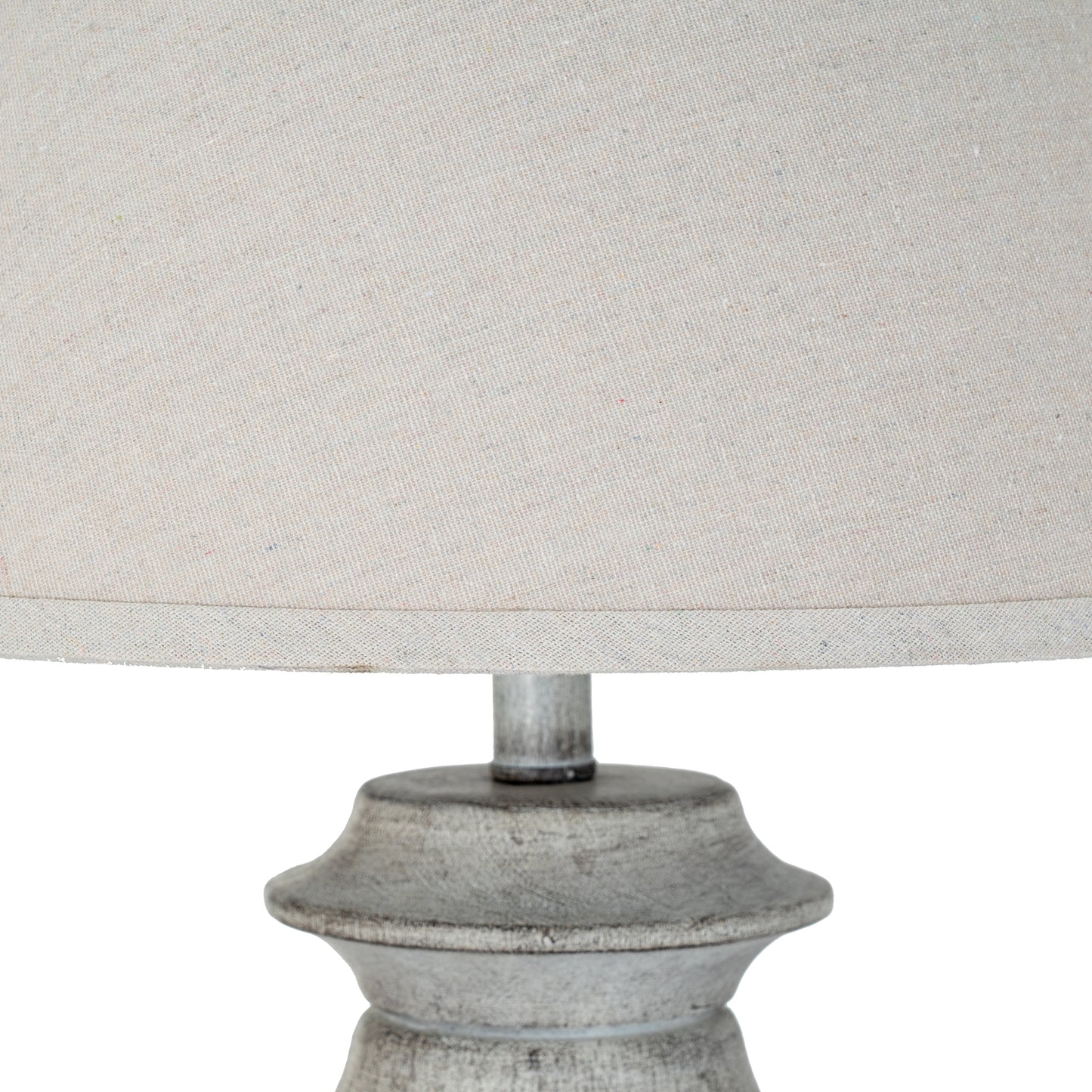 Close-up of a lamp with a textured base and light gray fabric shade on a white background