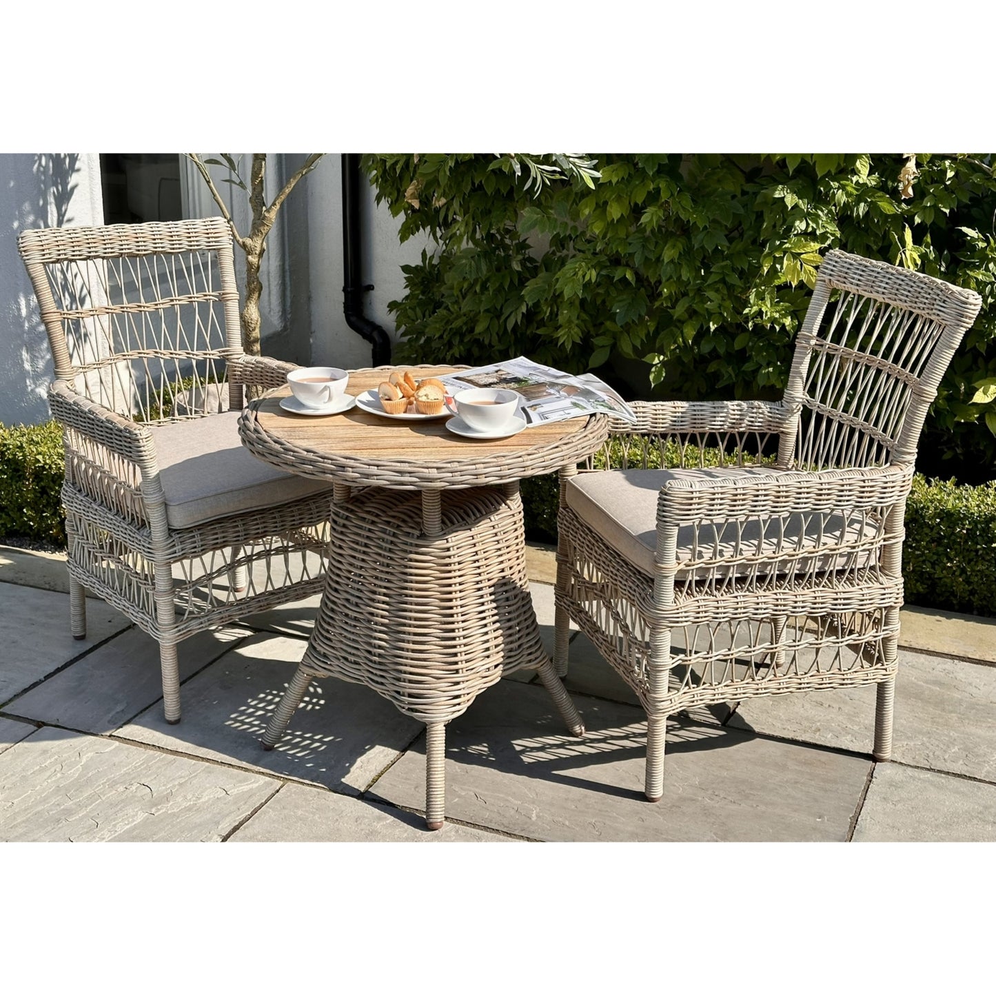 Wicker outdoor furniture set with a small table and two chairs on a patio.