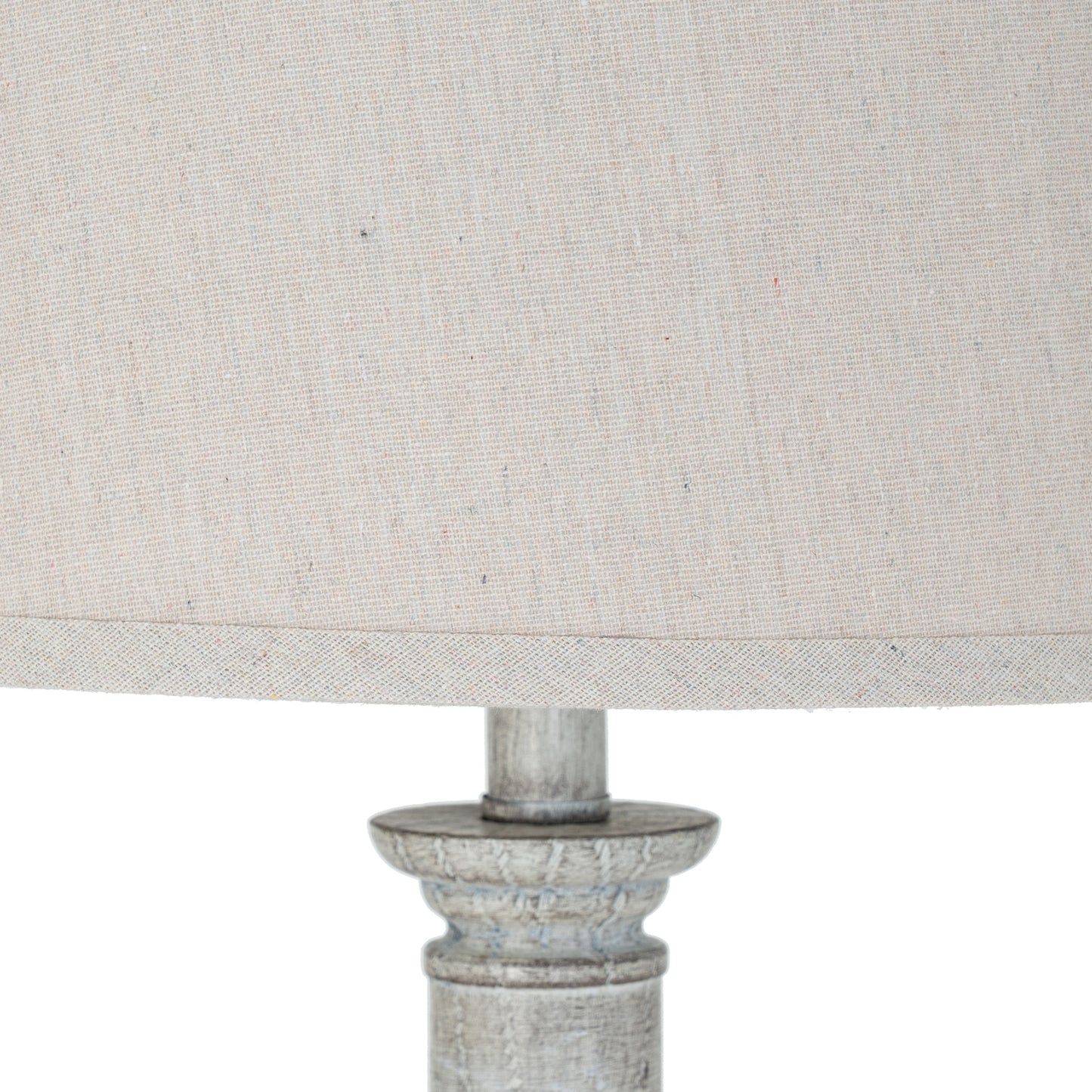 Close-up of a lamp with a textured beige shade and metallic base on a white background