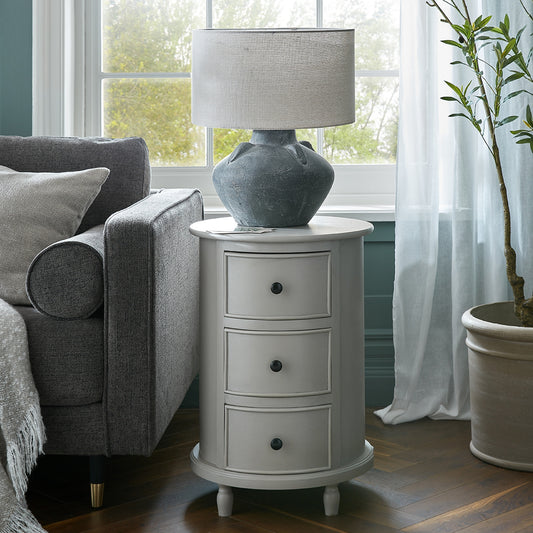 Gray side table with lamp next to a gray sofa in a living room.