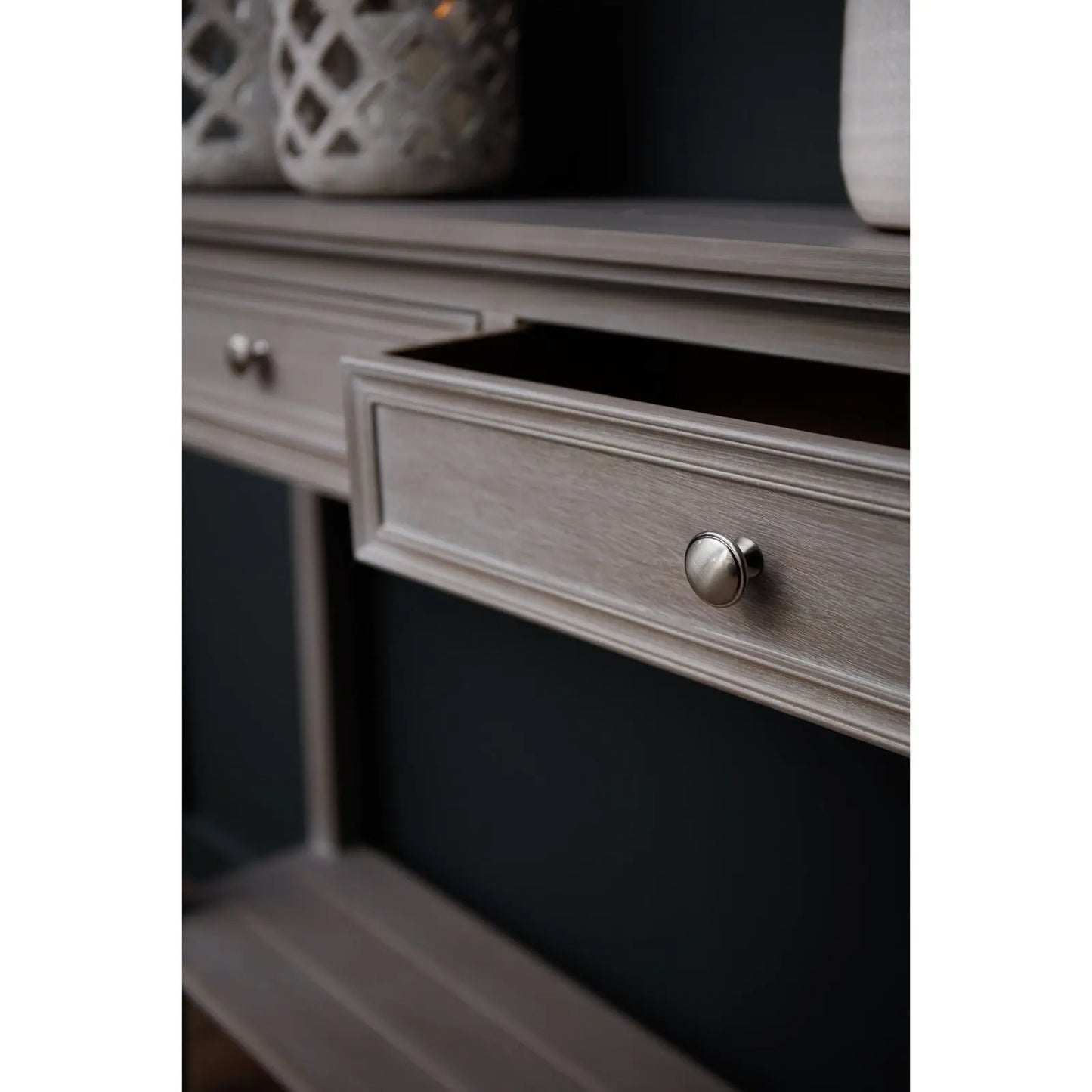 Close-up of a wooden drawer with a metallic handle on a dark background