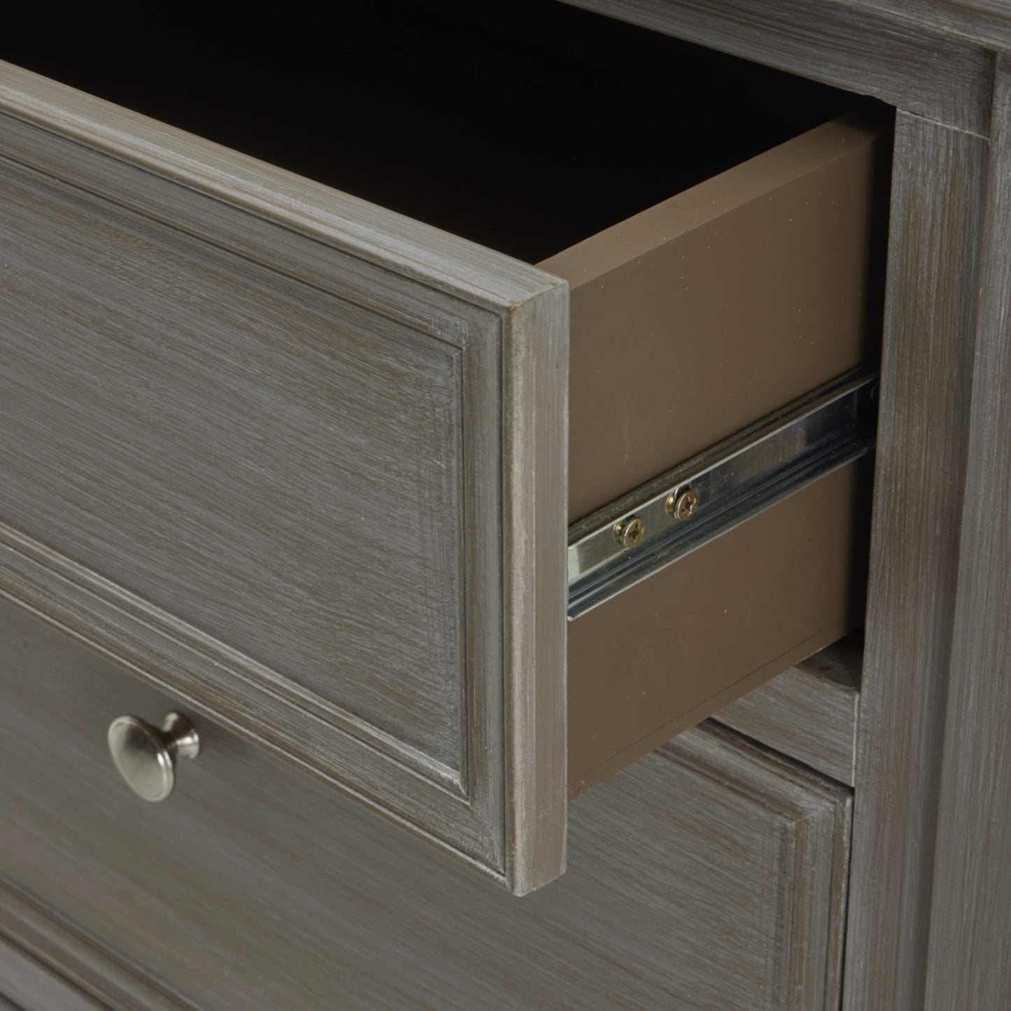 Open drawer of a wooden dresser with a metal handle.