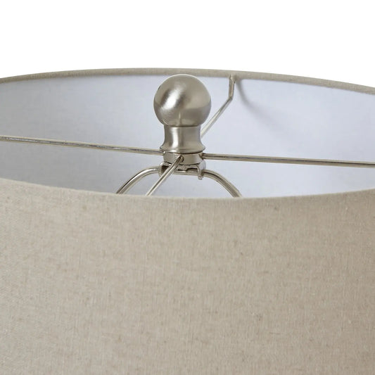 Close-up of a lamp with a beige fabric shade and metallic base.