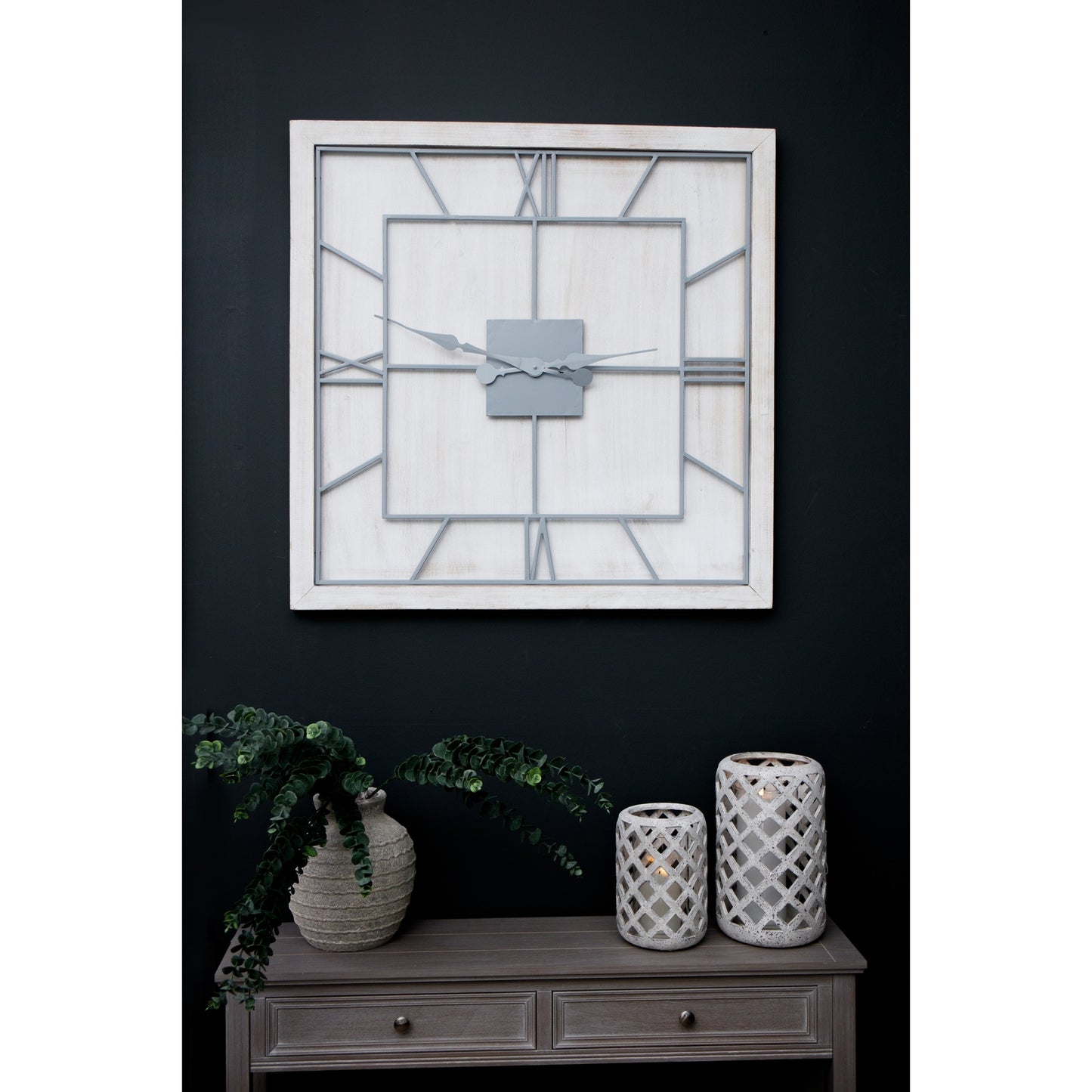 Decorative wall clock with geometric design on a dark wall above a wooden console table.