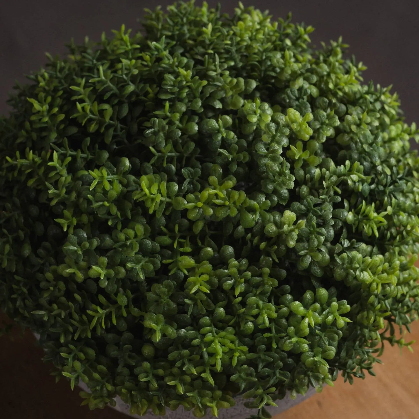 Close-up of a spherical artificial topiary plant with a dark background