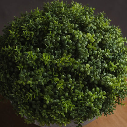 Close-up of a spherical artificial topiary plant with a dark background