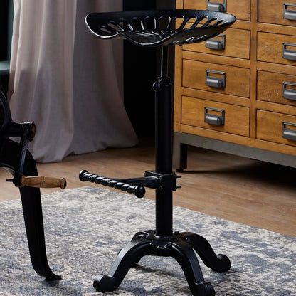 Black adjustable stool with a wooden handle in a room setting.