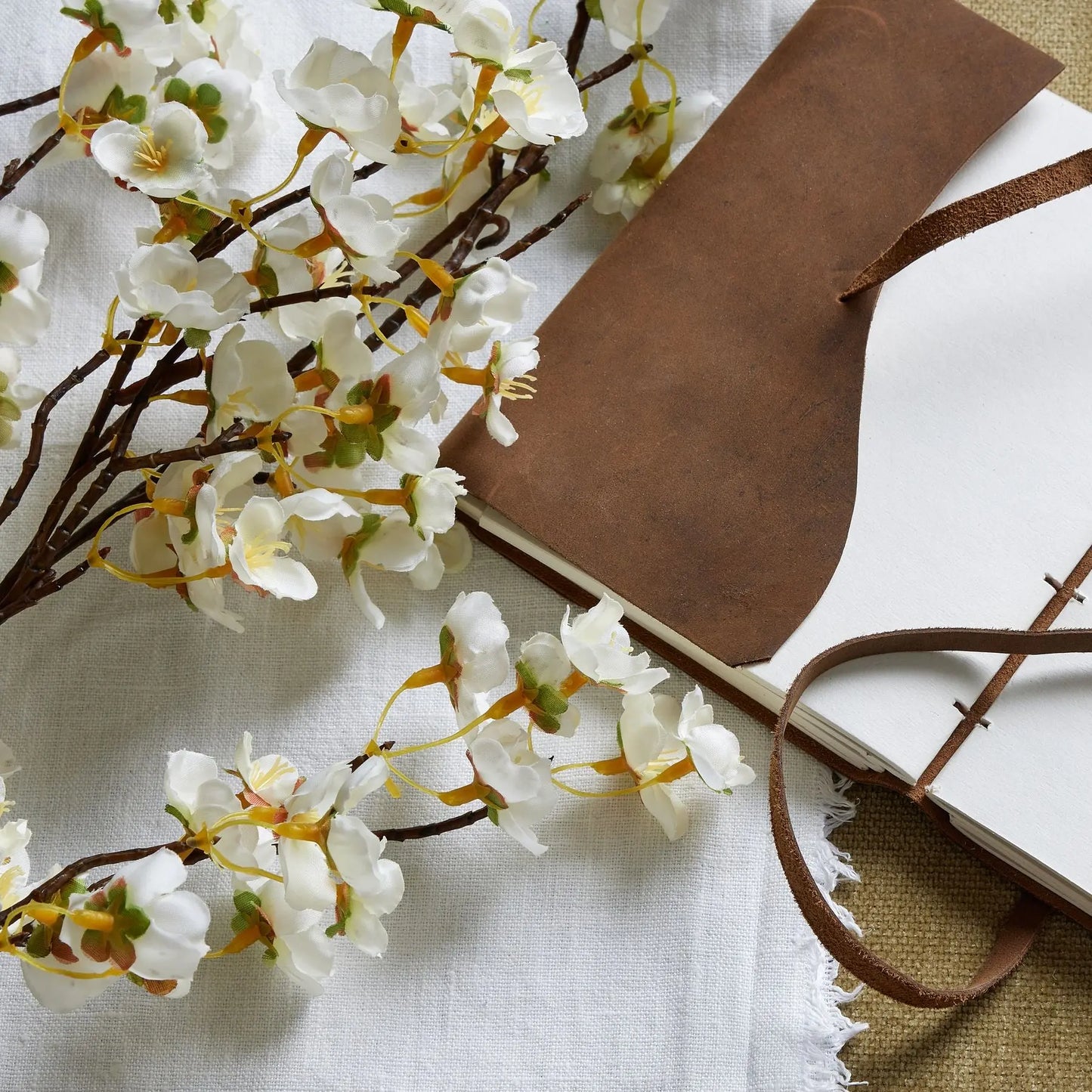Brown leather-bound book with white flowers on a light fabric background