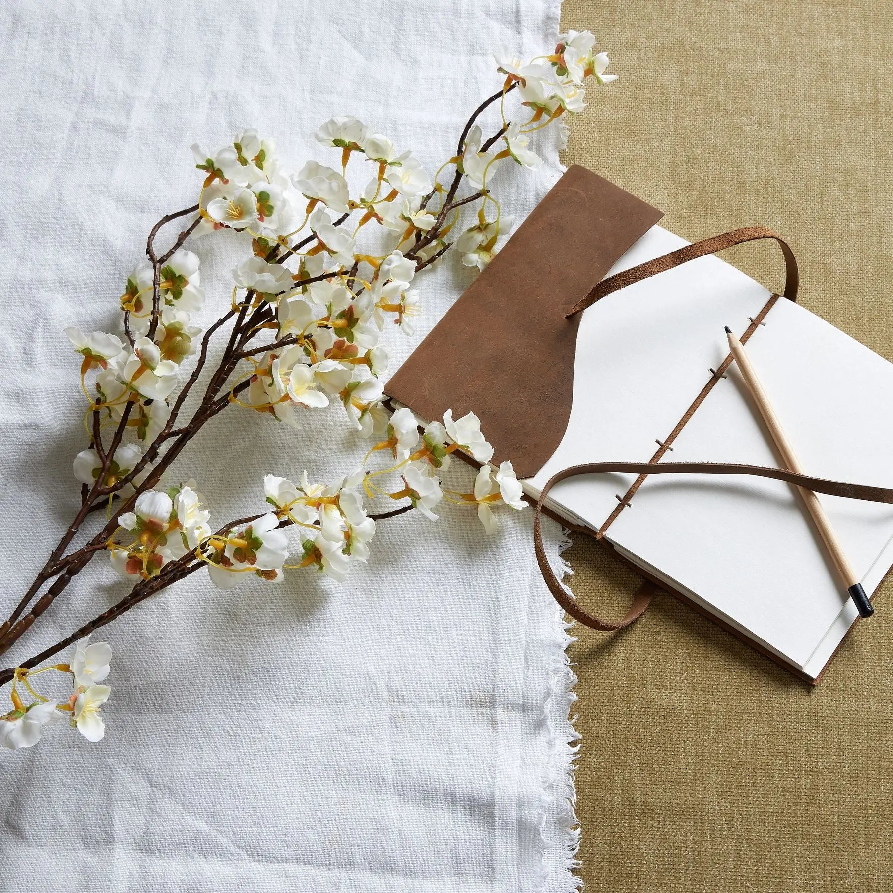 Floral branch with a notebook and pen on a textured surface