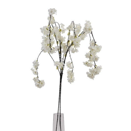 Artificial white floral branch in a clear glass vase on a white background