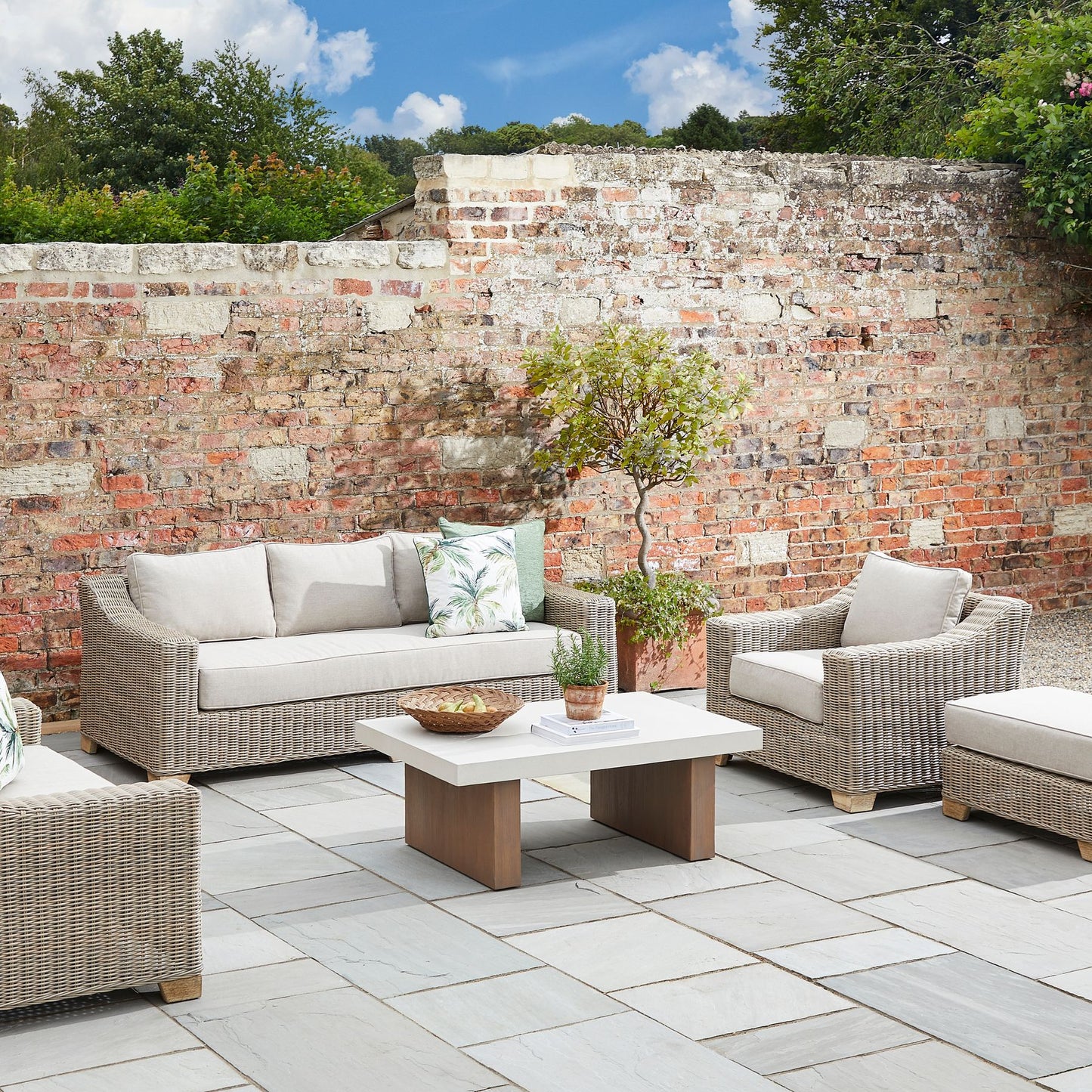 Outdoor patio setting with wicker furniture against a brick wall.