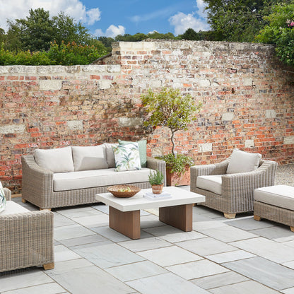 Outdoor patio setting with wicker furniture against a brick wall.