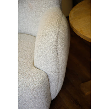 Close-up of a textured gray cushion on a chair with a wooden table in the background.