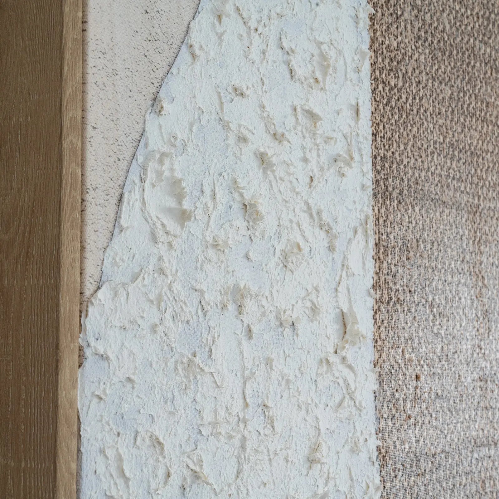 Close-up of a textured wall with three different finishes: wood, stone, and carpet.