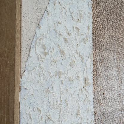 Close-up of a textured wall with three different finishes: wood, stone, and carpet.