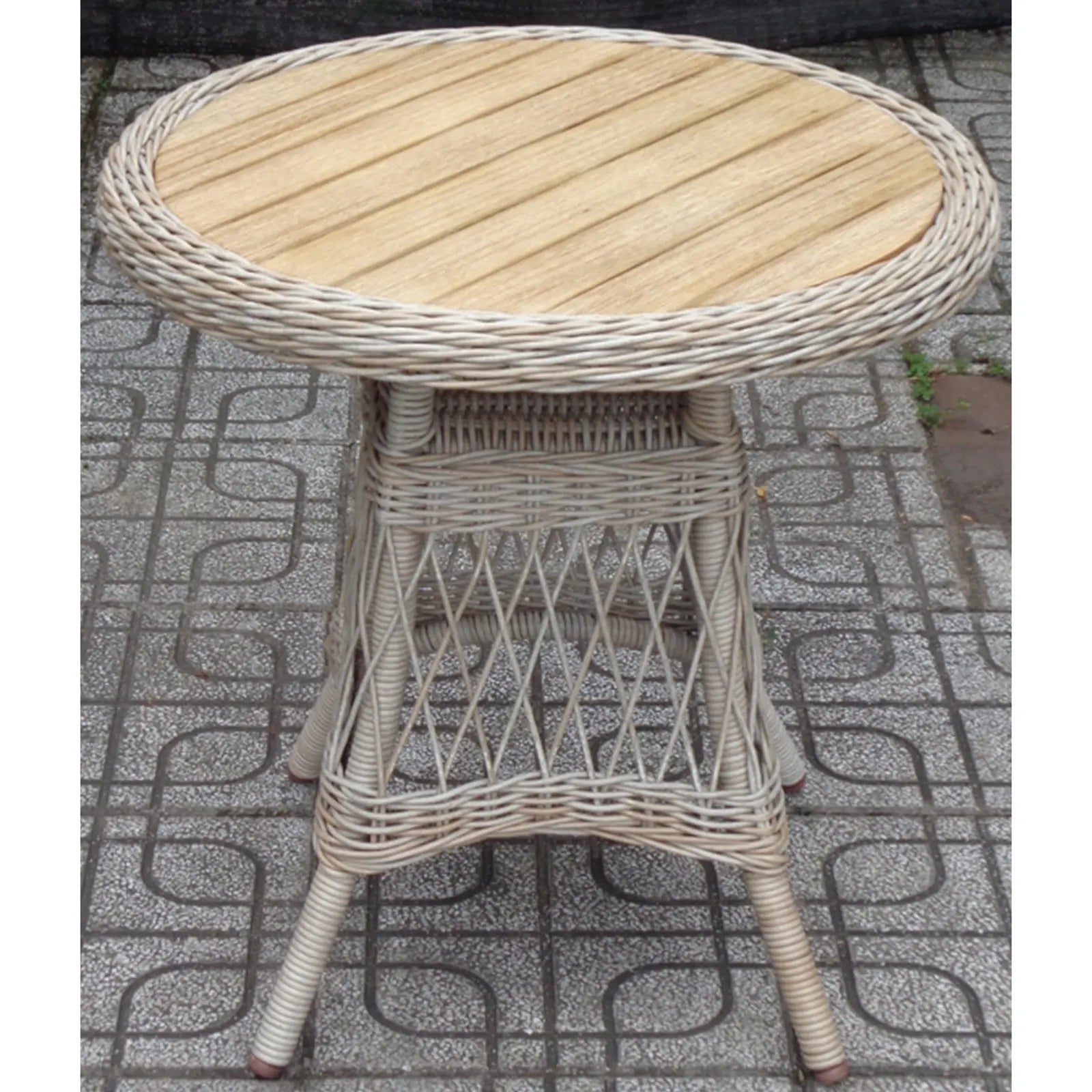 Round wicker table with wooden top on a patterned pavement
