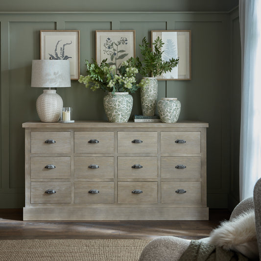 Wooden dresser with decorative items against a wall with framed artwork.