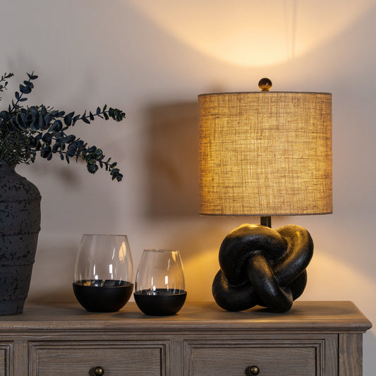 Decorative lamp and vases on a wooden surface with a warm glow.