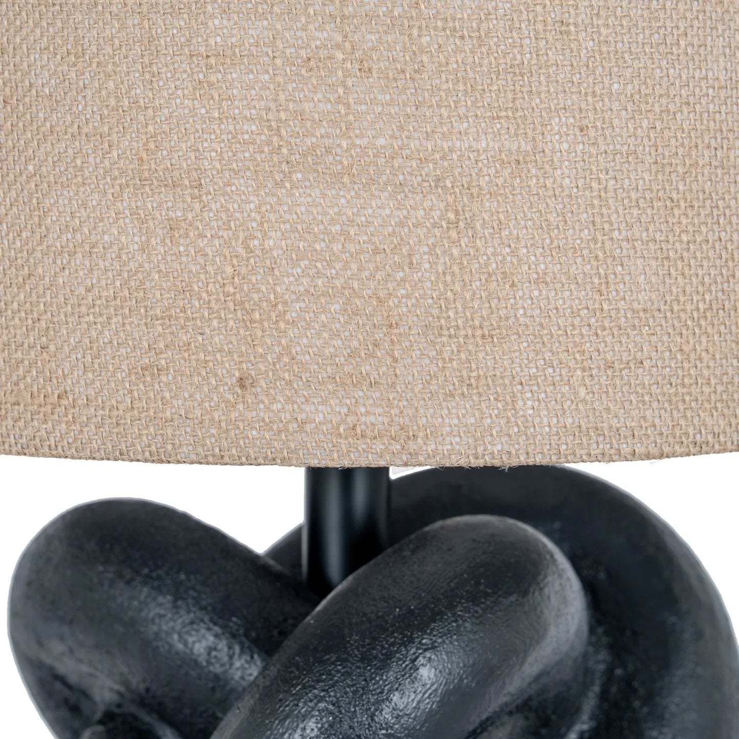 Close-up of a lamp with a beige fabric shade and black metal base.