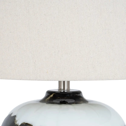 Close-up of a lamp with a white shade and black and white base.