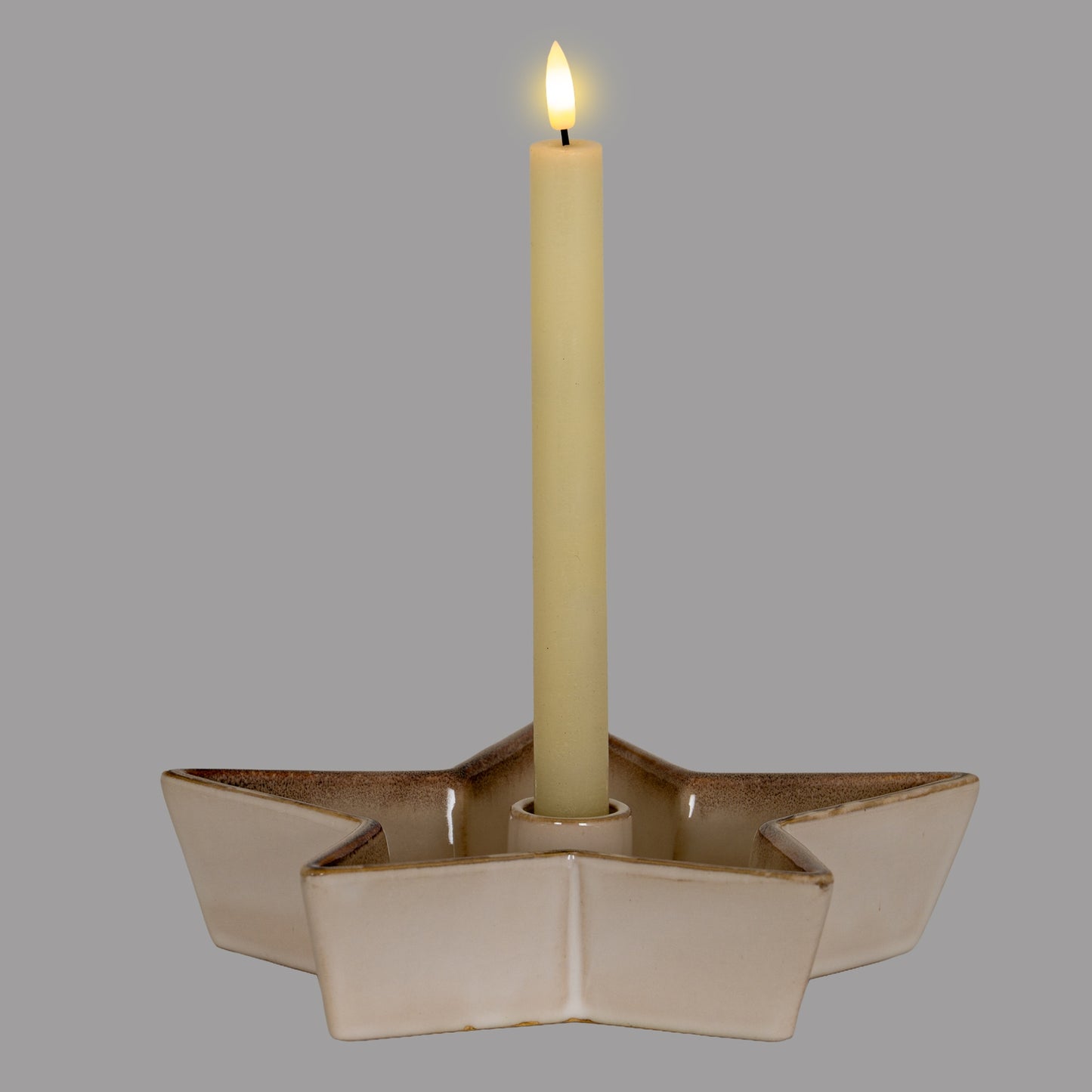 Beige ceramic star-shaped candle holder with a lit candle on a gray background