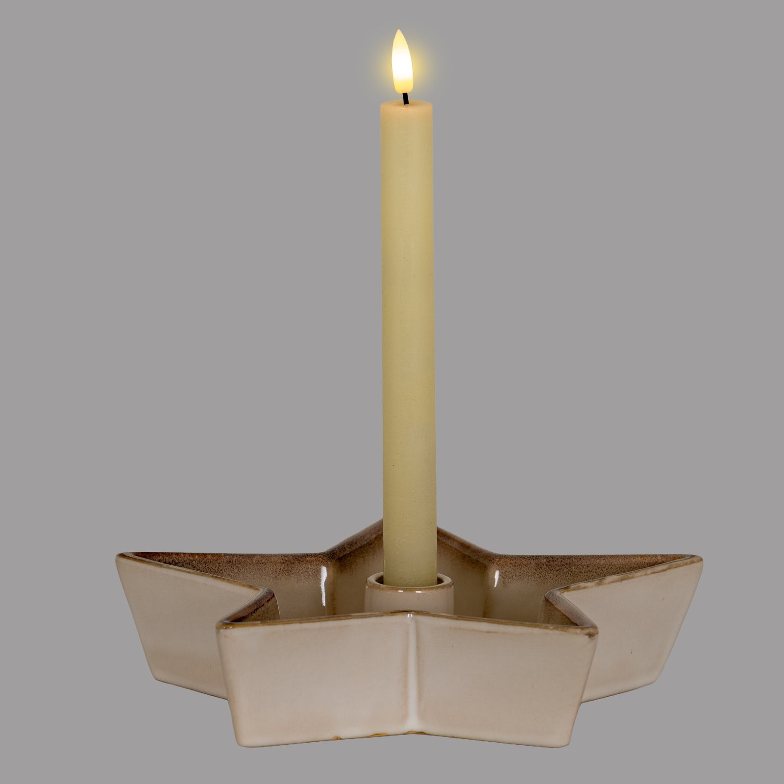 Beige ceramic star-shaped candle holder with a lit candle on a gray background
