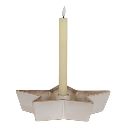 Beige ceramic candle holder with a lit candle on a white background
