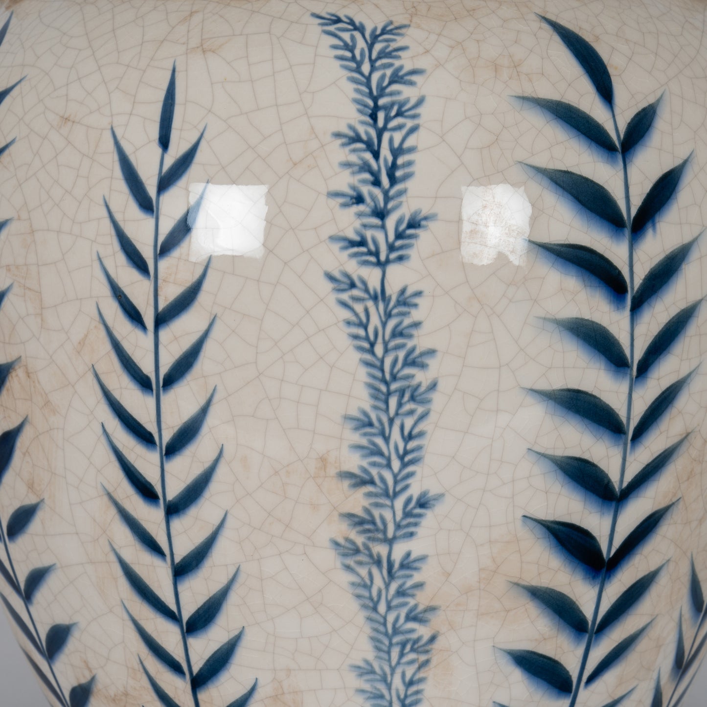Decorative tile with blue leaf patterns on a beige background