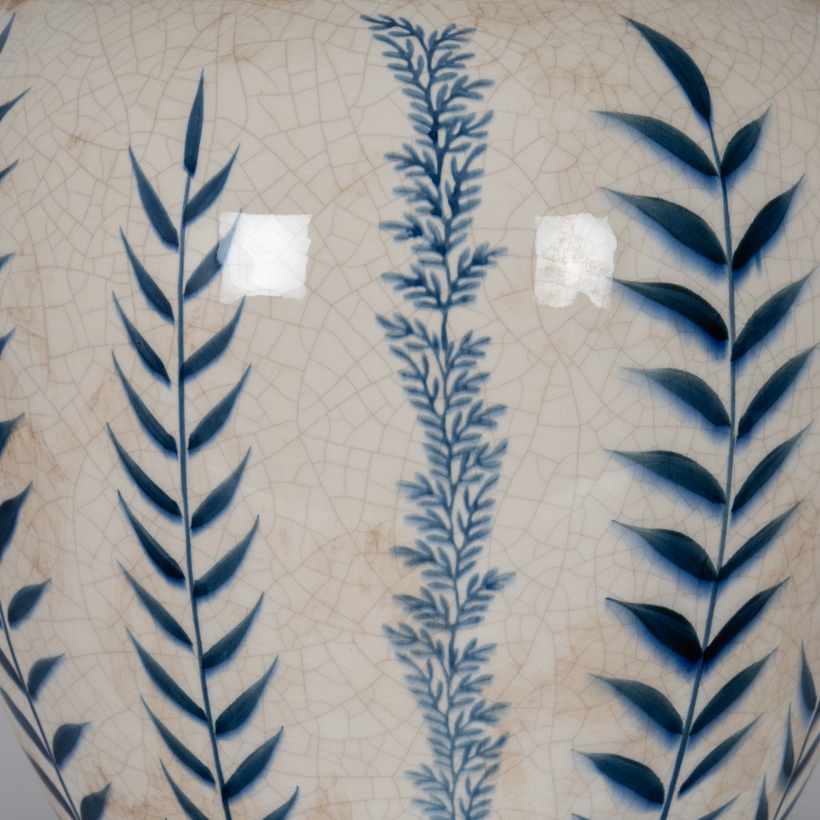 Decorative tile with blue leaf patterns on a beige background