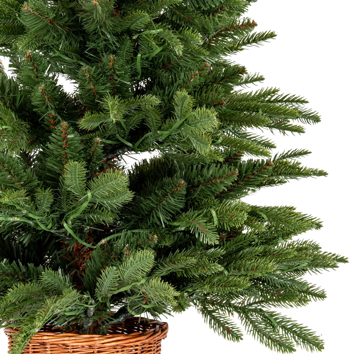 Close-up of a green artificial Christmas tree with a wicker basket base on a white background