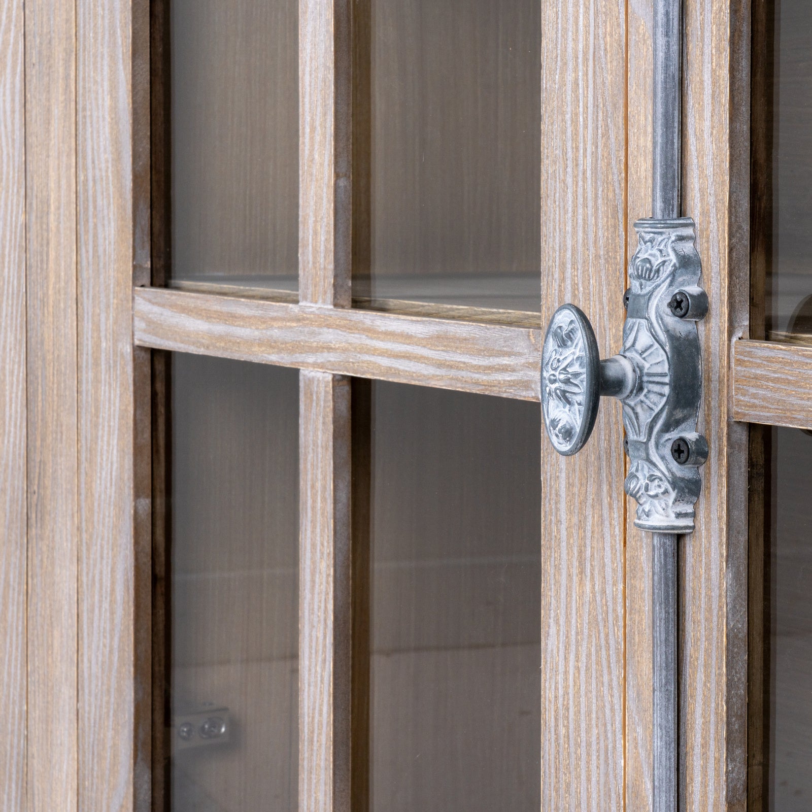 Close-up of a wooden door with glass panels and an ornate metal handle.
