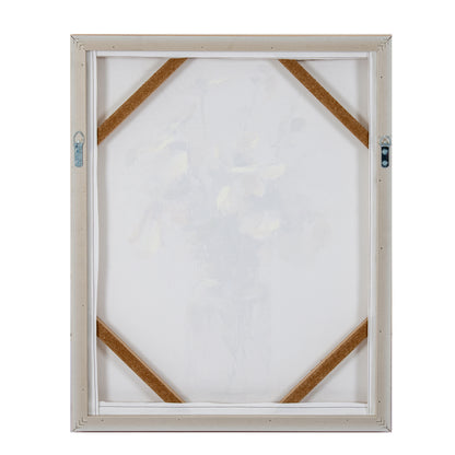 The back view of a square canvas print in a light beige frame, showing the white stretched canvas, corner support strips, and hanging hardware on a plain white background.