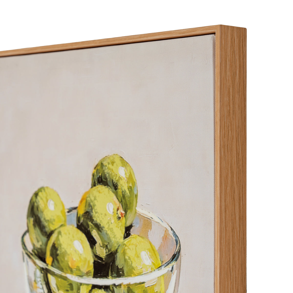 A framed still life painting showing green olives in a glass bowl, with a light wood frame visible against a white background.