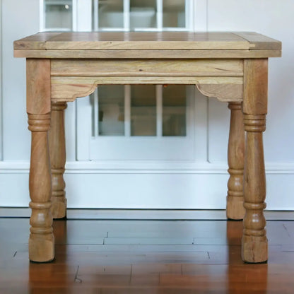 Wooden table with turned legs in a room with white walls and wooden floor.