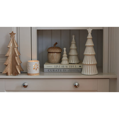 Decorative items including trees and a candle on a shelf with a neutral background
